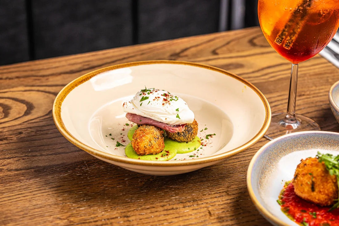 a wooden table topped with plates of food and a glass of wine